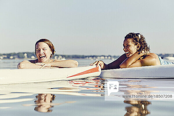Two young female friends on standup paddle board in Casco Bay  Maine