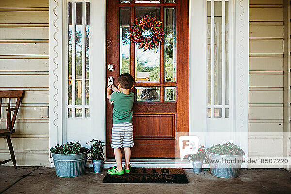 Young boy opening front door in summer