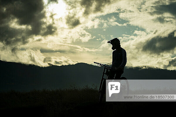 Mountain Biker sitting on bike with mountains silhouette washington