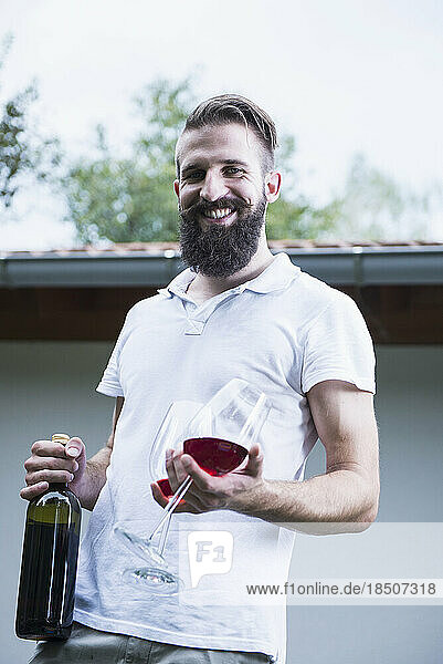 Portrait of a young man holding red wine with glasses  Bavaria  Germany