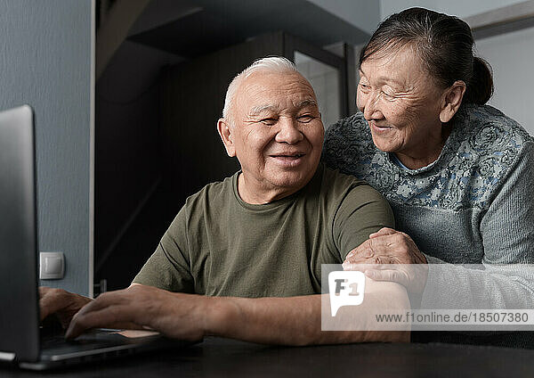 Senior couple at home using laptop for education or online shopping