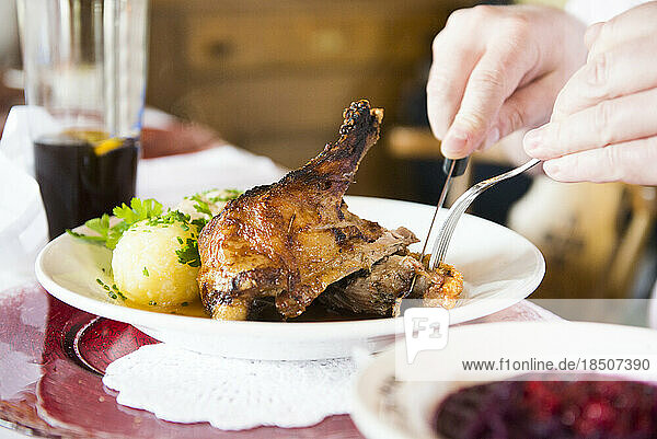 Man eating duck meat with potato dumpling at restaurant table  Bavaria  Germany