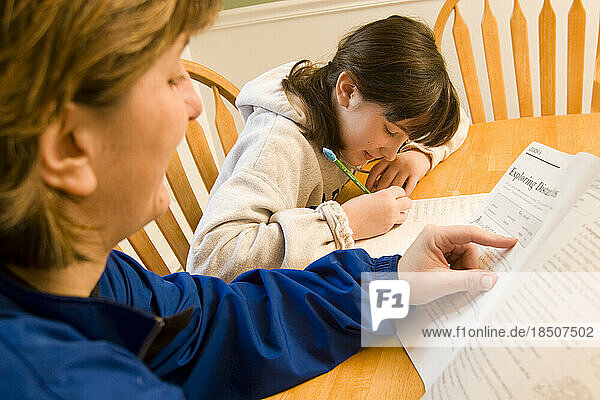 A mother helps her ten-year-old daughter with her homework.