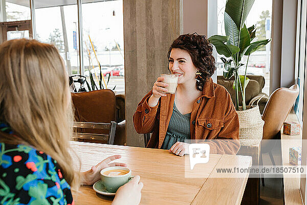 Two happy women meeting up for coffee inside