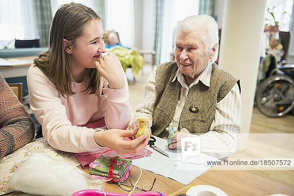 Senior woman with girl holding handmade crochet chick at rest home
