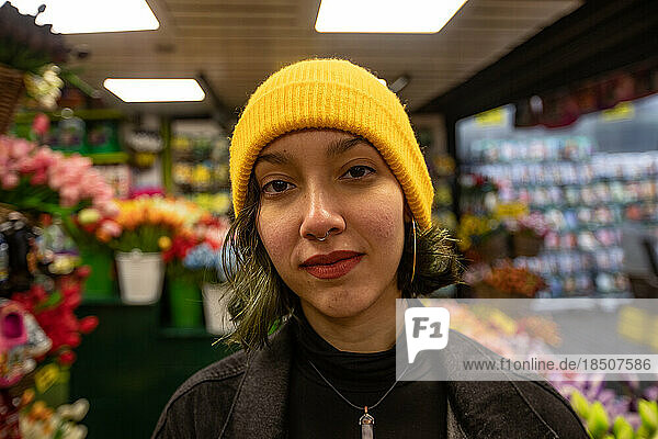 Portrait of young woman in yellow hat standing in florist.