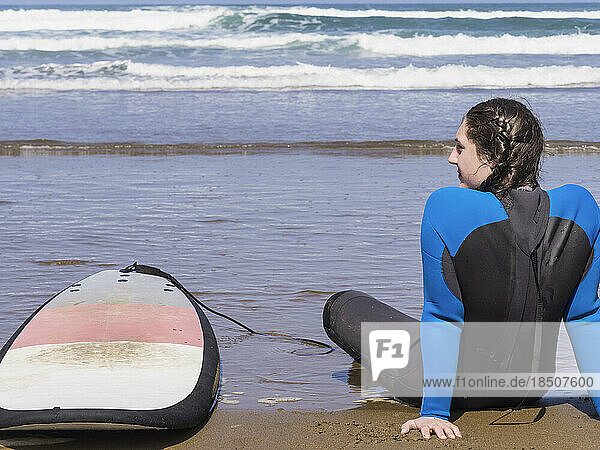 Woman relaxing with surfboard at Sopela Beach  Biscay  Basque Country  Spain