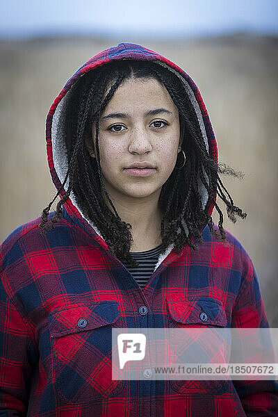 portrait of biracial young woman with serious expression wearing hood