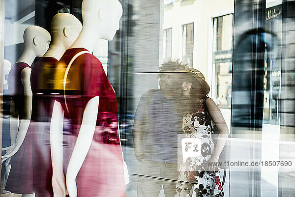 Couple in the city looking at clothing store window