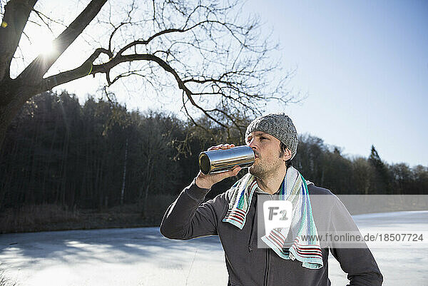 Man drinking water after workout by frozen lake