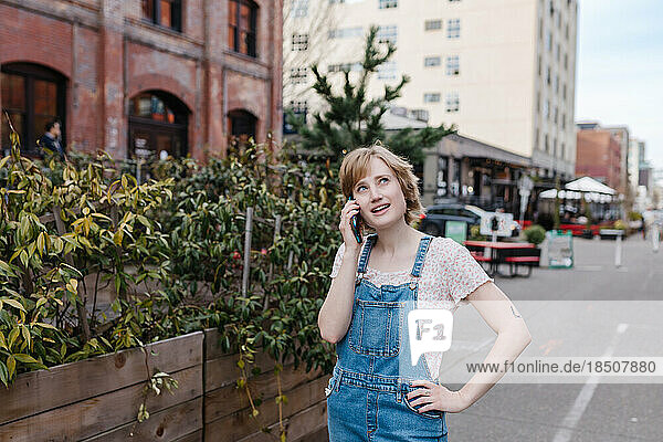 Thoughtful woman talking on phone while walking outside downtown