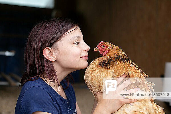 Girl face to face with hen in chicken coop
