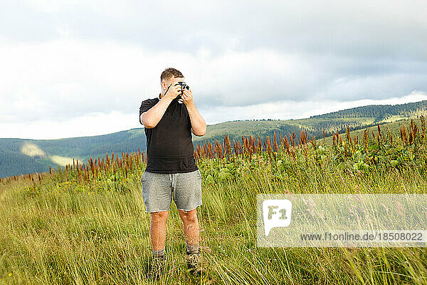 guy in black t-shirt takes pictures of Carpathians landscapes