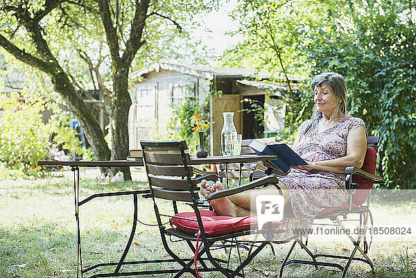 Senior woman reading a book in the garden  Altötting  Bavaria  Germany