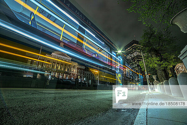 Long exposure city bus lights passing by State House building.