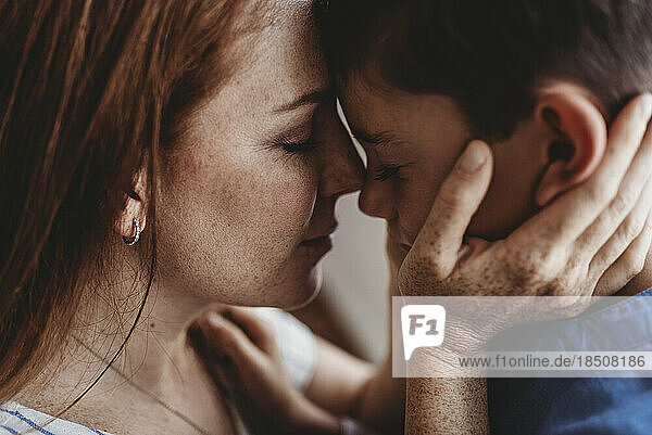 Close up side view of young mother embracing young boy in studio