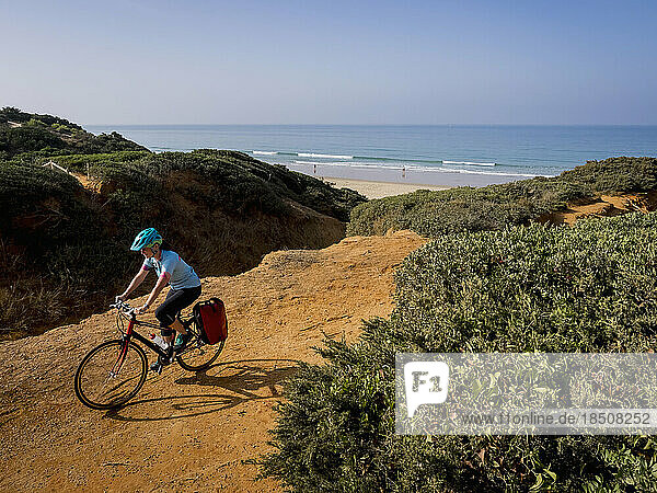 Mountain biker riding dirt track near beach and sea