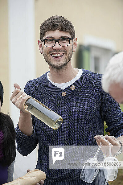 Mid adult man holding white wine and wine glasses  Bavaria  Germany