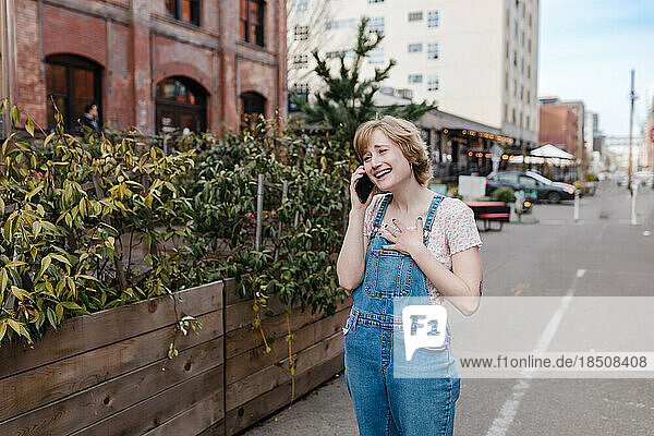 Happy woman talking on phone walking downtown