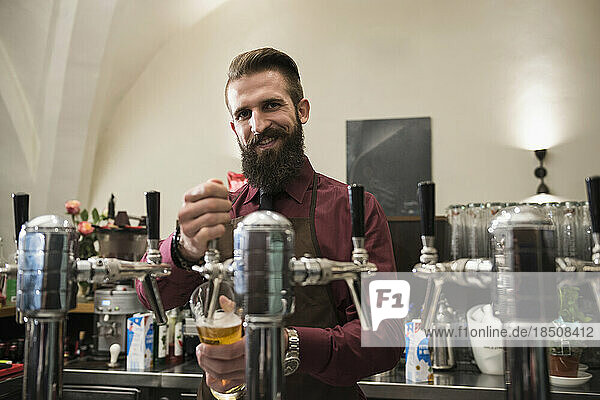 Portrait of smiling restaurant owner filling glass of beer