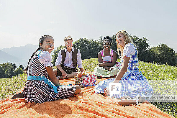 Happy teenage friends relaxing on picnic blanket  Bavaria  Germany