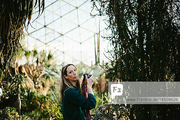 Woman with camera and eye contact in green dome greenhouse