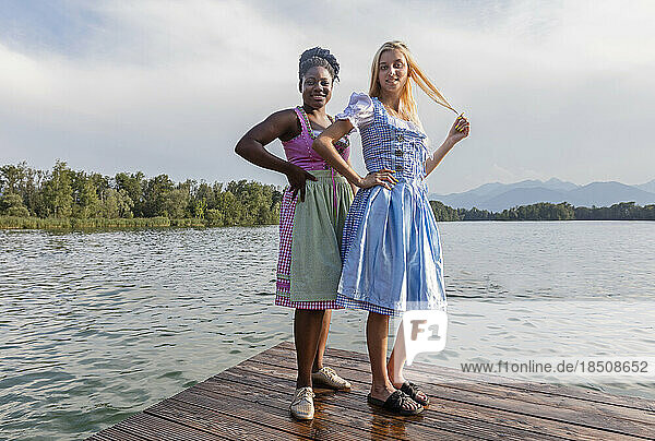 Teenage friends standing on pier over lake  Bavaria  Germany