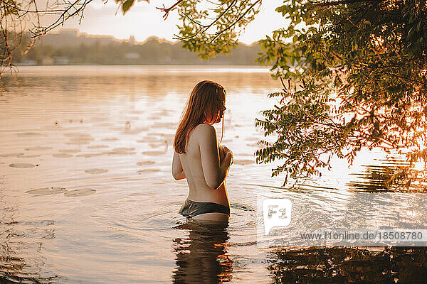 Topless woman in water at sunset