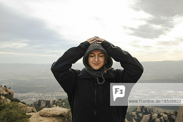 Portrait of a girl in a jacket and balaclava on top of a mountain