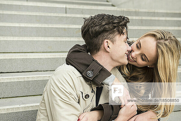 Young couple sitting on stairs and kissing  Munich  Bavaria  Germany