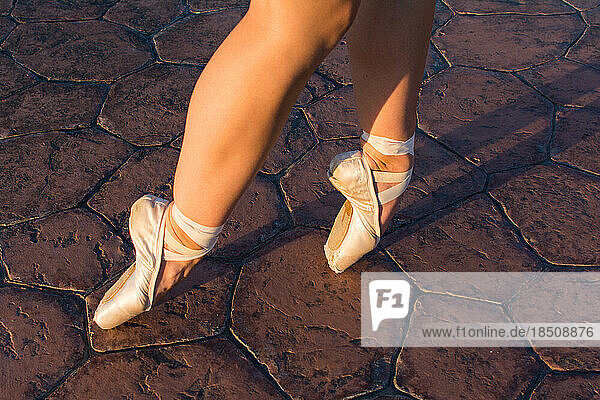 On pointe ballerina feet at golden hour on rock path