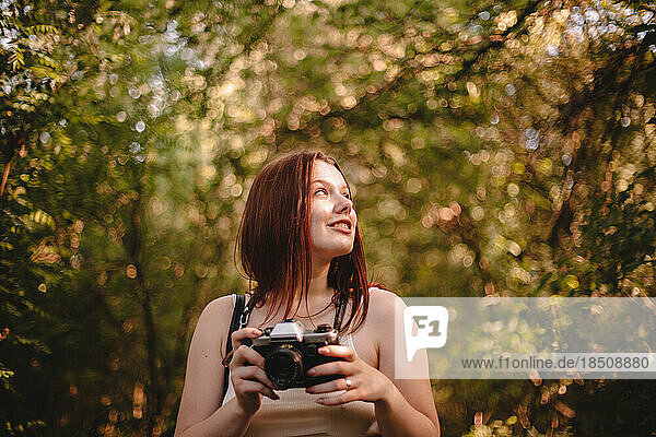 Young woman holding camera in forest