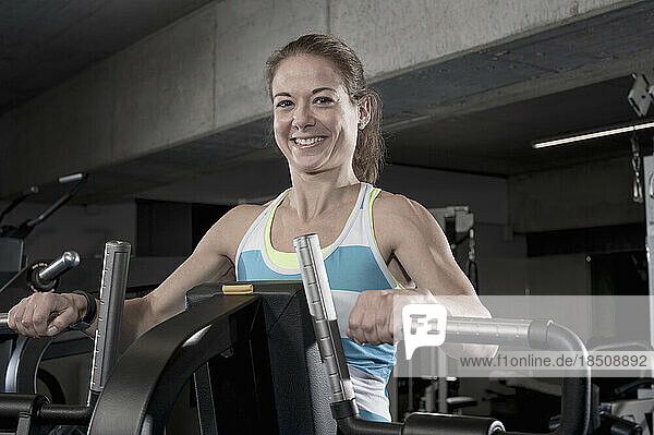 Portrait of a mid adult woman doing exercise on exercise machine in the gym  Bavaria  Germany
