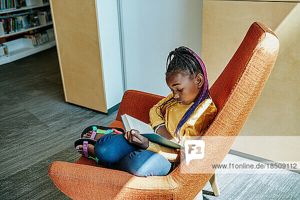 Young girl reading in quiet corner alone