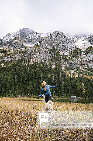 Girl with her dog hiking in the mountains with fall larches