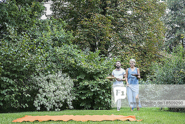 Young couple carrying food and walking at picnic blanket  Bavaria  Germany