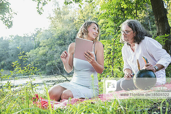 Couple on picnic using tablet  eating watermelon by lake  Bavaria  Germany