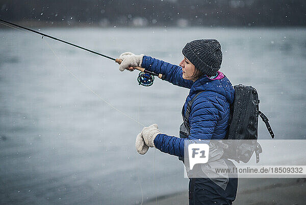 Woman angler casting fly rod in snow storm