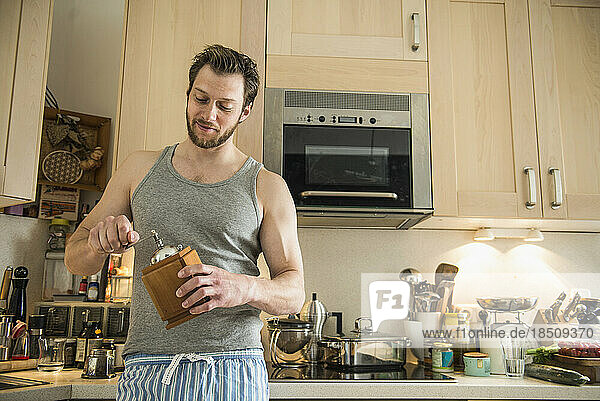 Man standing in kitchen and grinding coffee grinder  Munich  Bavaria  Germany