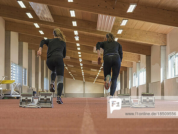 Two women running in athletics hall on tartan track  Offenburg  Baden-Württemberg  Germany