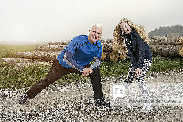 Father with his daughter stretching legs on footpath and smiling during dawn  Bavaria  Germany