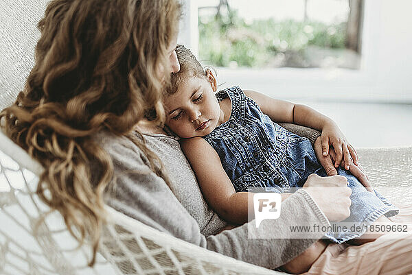 Young girl and mother cuddling on hammock in natural light studio