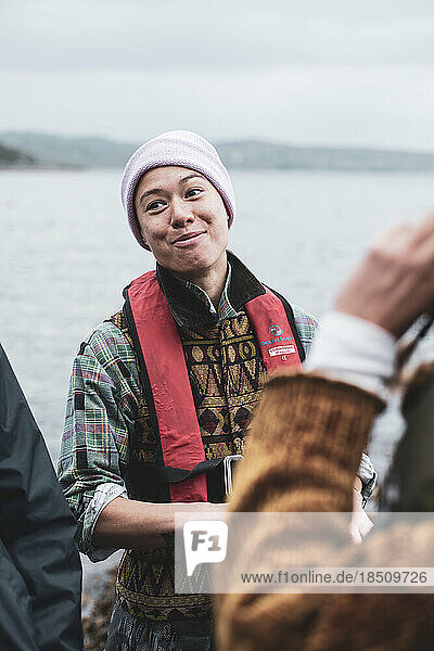 multicultural queer woman in life vests in conversation on boat