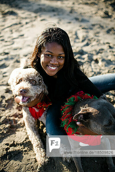 Young girl with two dogs smiles at camera on beach at sunset