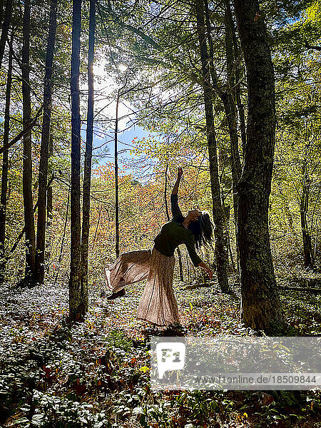 Woman dancing between trees in woods