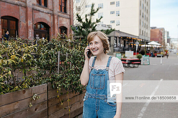 Laughing young woman talking on cell phone downtown