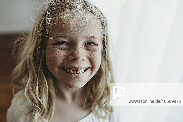 Portrait of young freckled smiling girl missing tooth