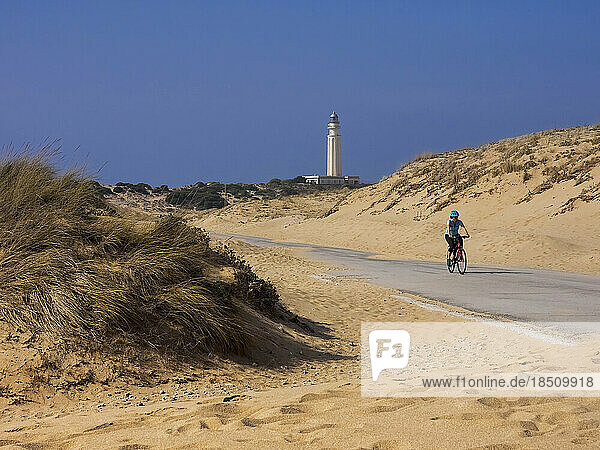 Mature woman cycling on road by sand dune