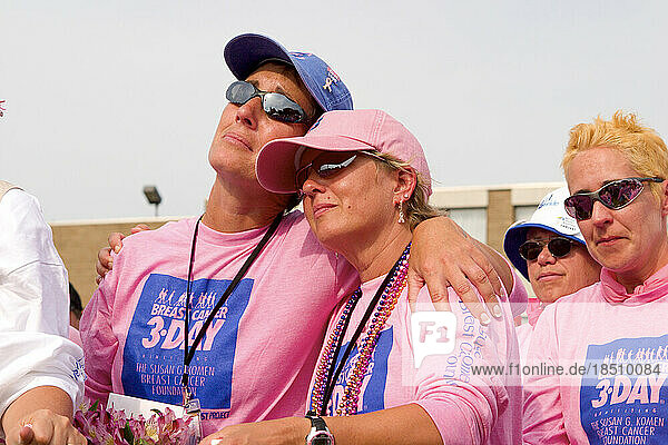 Breast cancer survivors in pink shirts embrace during the closing ceremonies of the Komen 3-Day walk for breast cancer in Detroi