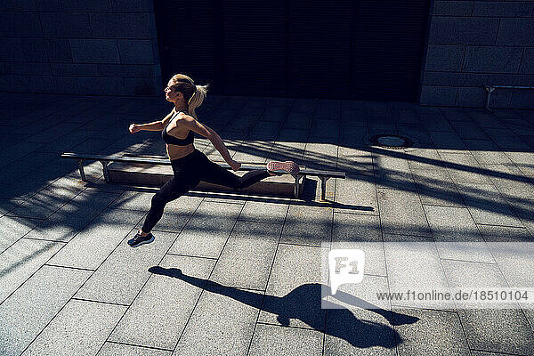 Blondie fit woman in black sportswear jogging outdoors workout